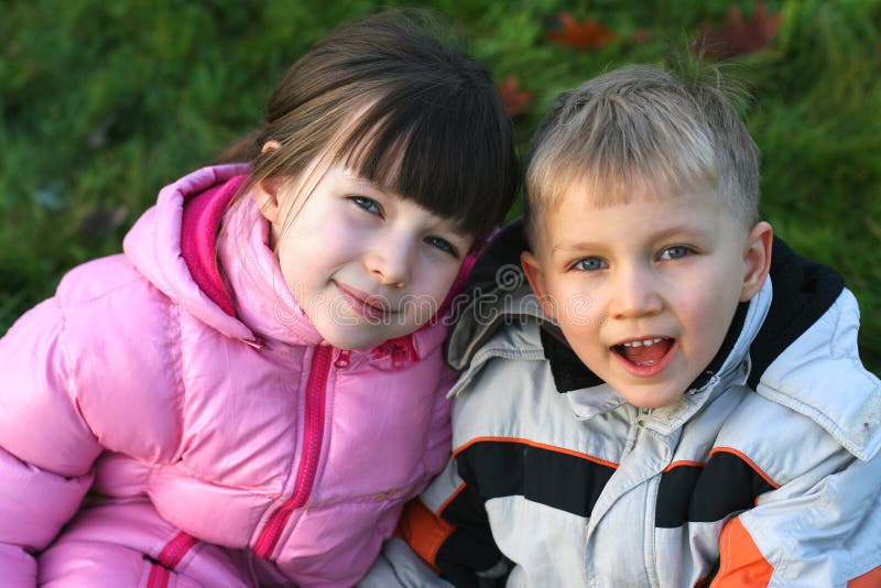 Portrait of a brother and sister sitting together outdoors in a meadow. Portrait of a brother and sister sitting together outdoors in a meadow.