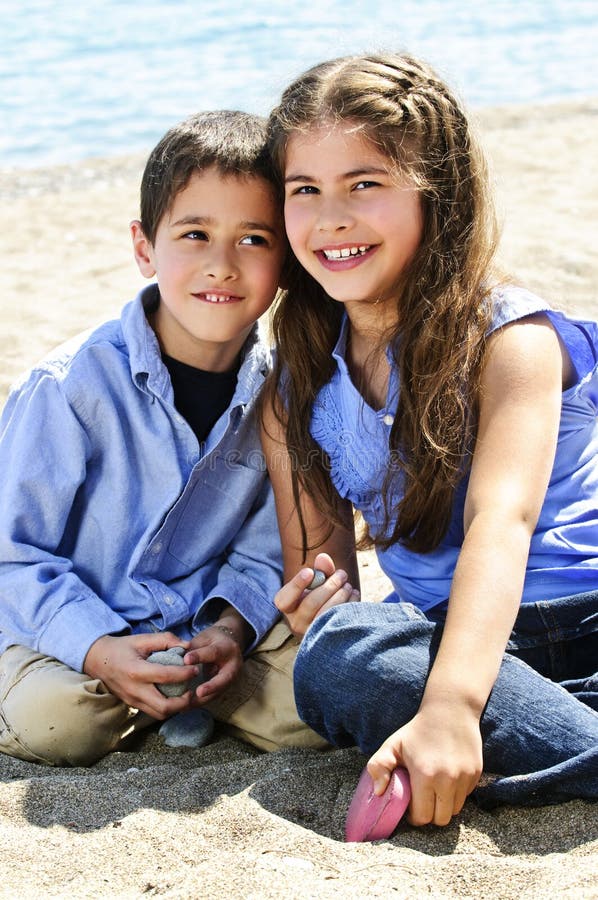 Portrait of brother and sister sitting on sand at the beach. Portrait of brother and sister sitting on sand at the beach