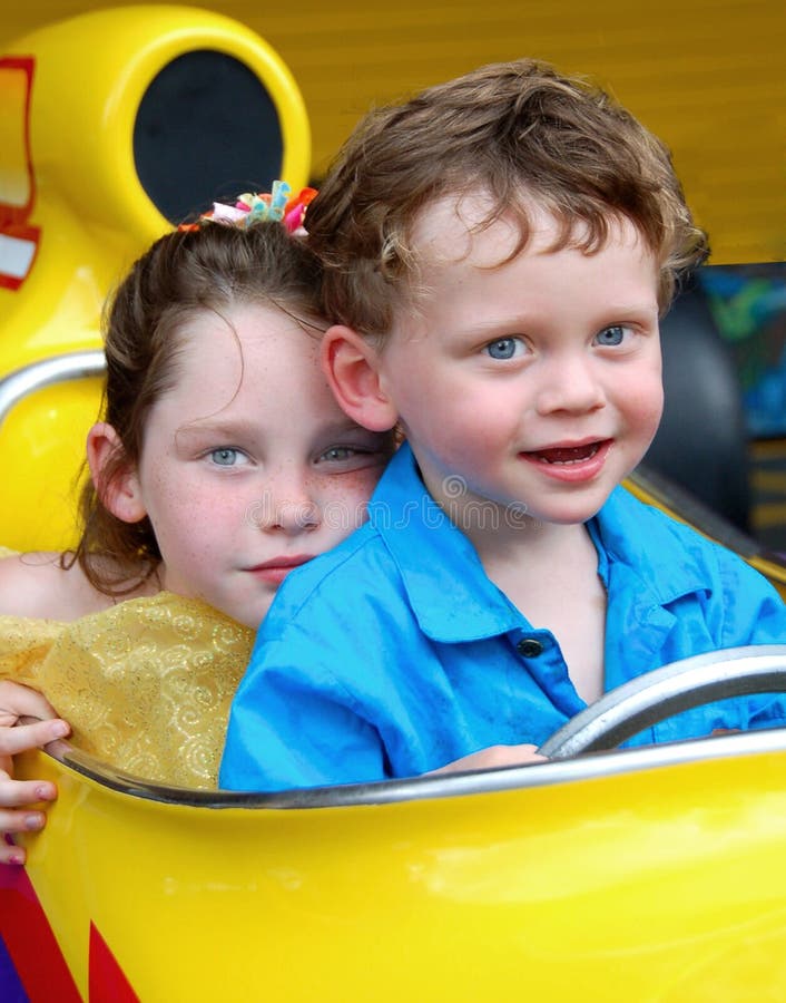 Young brother and sister sitting together in race car. Young brother and sister sitting together in race car