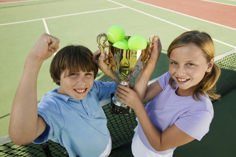 Brother and Sister on tennis court holding up Trophy, portrait, high angle view. Brother and Sister on tennis court holding up Trophy, portrait, high angle view