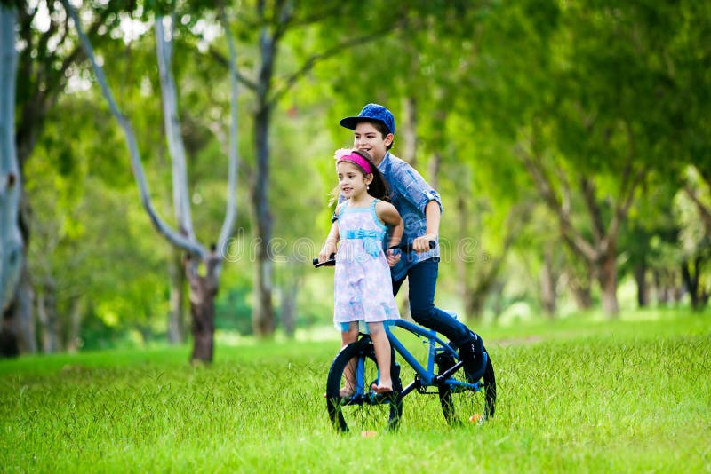 Brother taking his sister on a bike ride in the park. Brother taking his sister on a bike ride in the park