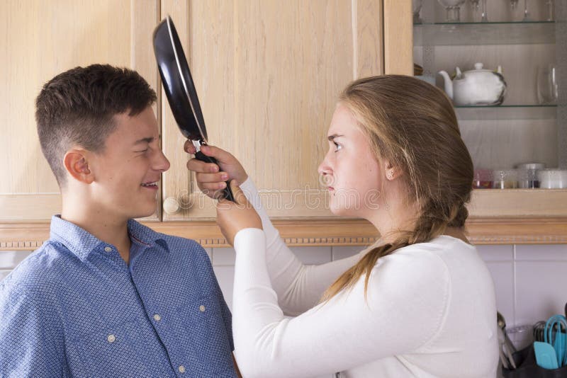Irmãos adolescentes que têm a luta na cozinha imagens de stock Irmãos adolescentes que têm a luta na cozinha imagens de stock