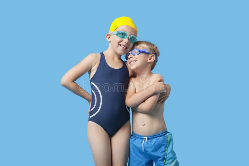 Irmãos novos felizes no roupa de banho com braço ao redor sobre o fundo azul fotos de stock Irmãos novos felizes no roupa de banho com braço ao redor sobre o fundo azul fotos de stock
