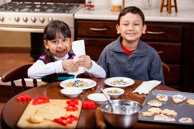 Cute Latin siblings baking and decorating Christmas cookies and smiling. Cute Latin siblings baking and decorating Christmas cookies and smiling