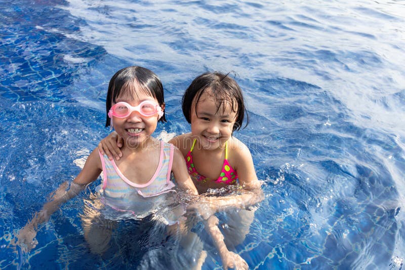 Irmãs chinesas pequenas asiáticas que jogam na piscina fotos de stock Irmãs chinesas pequenas asiáticas que jogam na piscina fotos de stock
