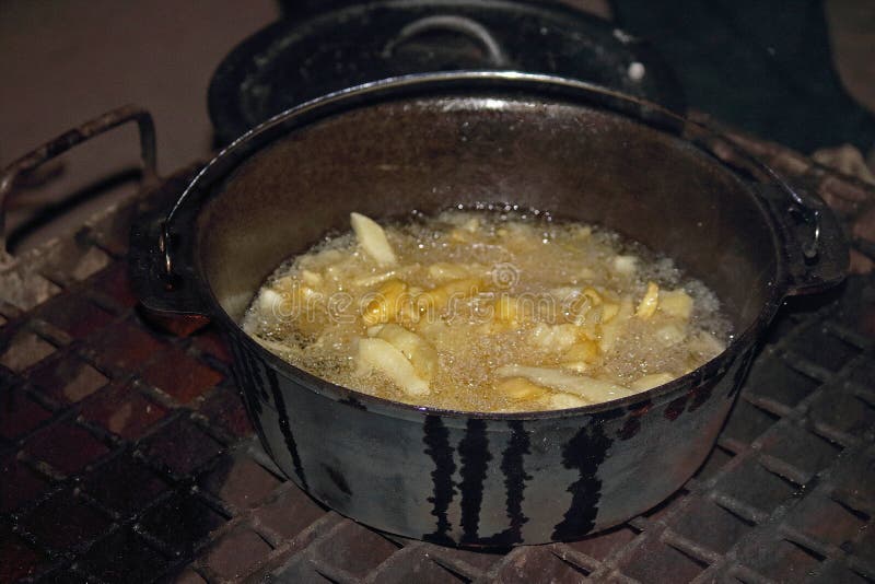 POTATO CHIPS FRYING in OIL on an OPEN FIRE in an IRON POT Stock Photo