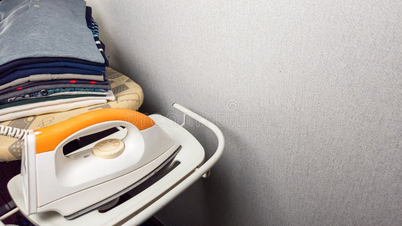 Ironing board with iron and neatly folded clothes ready for use stock images