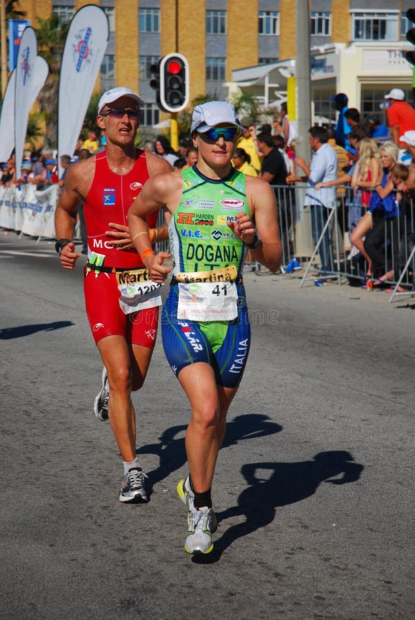 Female professional triathlete Martina Dogana from Italy running on the road, followed by male athlete Martin Liebeck from France at the Ironman South Africa 2010 in Port Elizabeth (Nelson Mandela Bay) on 25.04.2010. Female professional triathlete Martina Dogana from Italy running on the road, followed by male athlete Martin Liebeck from France at the Ironman South Africa 2010 in Port Elizabeth (Nelson Mandela Bay) on 25.04.2010