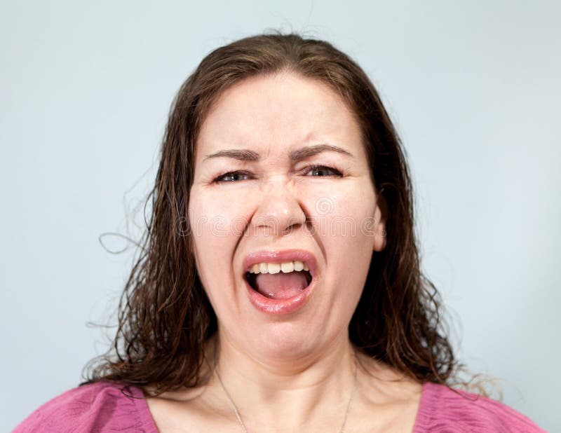 Irritation und Ekel auf dem Gesicht einer erwachsenen Frau, Portrait auf grauem Hintergrund, Emotionen Serie lizenzfreie stockbilder