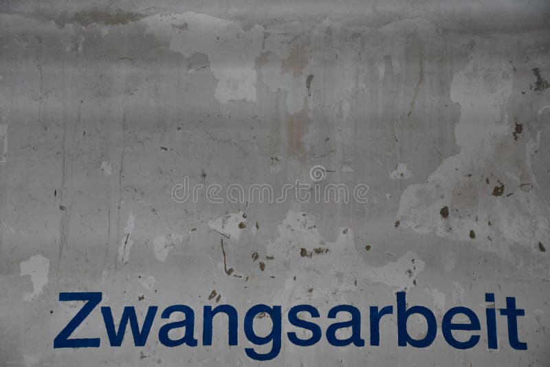 Inscription `Zwangsarbeit` forced labor written in block letters on white wall. Inscription `Zwangsarbeit` forced labor written in block letters on white wall