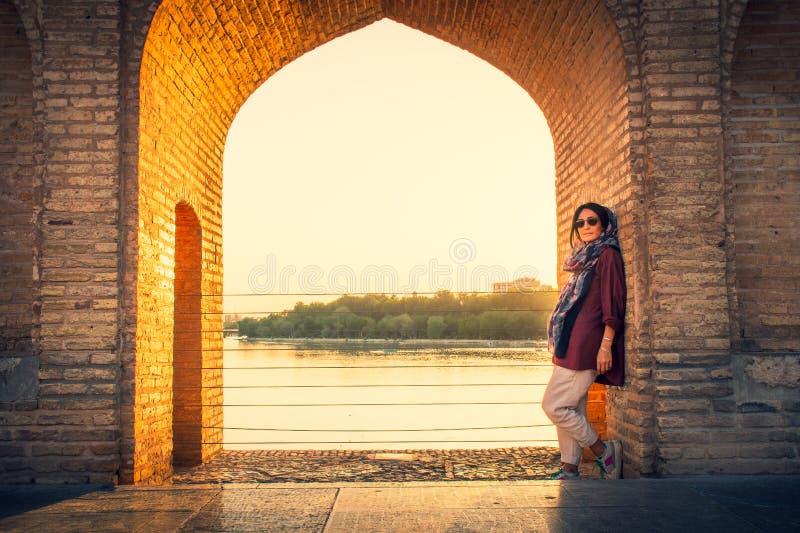 Isfahan, Iran - May 2022: woman stand on Sio Se Pol or Bridge of 33 arches, one of the oldest bridges of Esfahan and longest bridge on Zayandeh River. Isfahan, Iran - May 2022: woman stand on Sio Se Pol or Bridge of 33 arches, one of the oldest bridges of Esfahan and longest bridge on Zayandeh River.