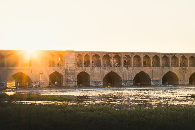 Isfahan, Iran - May 2022: people chill and socialize around SioSe Pol or Bridge of 33 arches, one of the oldest bridges of Esfahan and longest bridge on Zayandeh River. Isfahan, Iran - May 2022: people chill and socialize around SioSe Pol or Bridge of 33 arches, one of the oldest bridges of Esfahan and longest bridge on Zayandeh River.