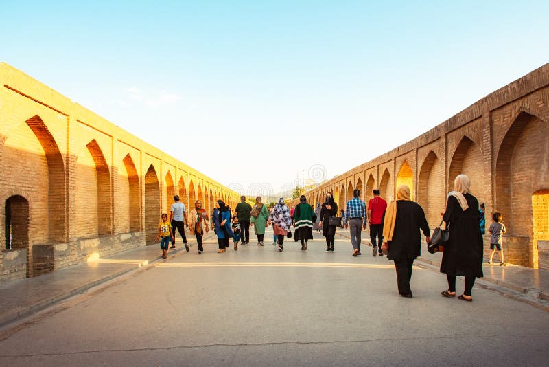 Isfahan, Iran - May 2022: people walk on Sio Se Pol or Bridge of 33 arches, one of the oldest bridges of Esfahan and longest bridge on Zayandeh River. Isfahan, Iran - May 2022: people walk on Sio Se Pol or Bridge of 33 arches, one of the oldest bridges of Esfahan and longest bridge on Zayandeh River.