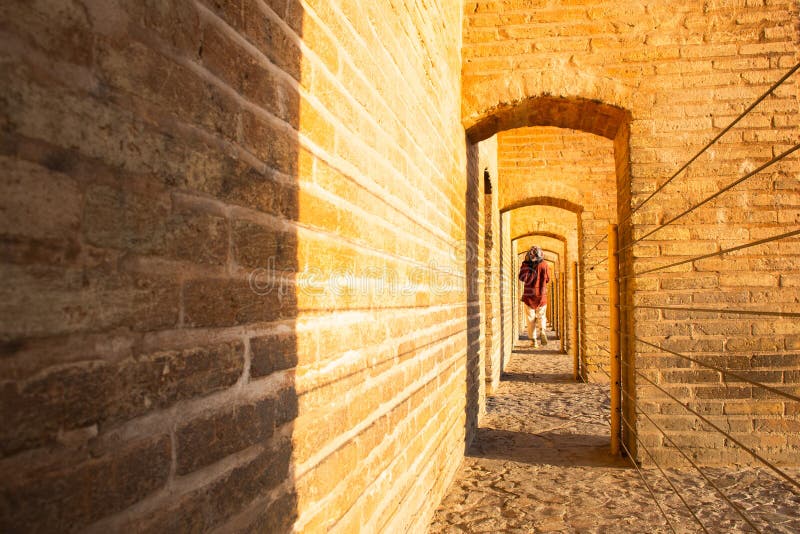 Isfahan, Iran - May 2022: back view woman walk on Sio Se Pol or Bridge of 33 arches, one of the oldest bridges of Esfahan and longest bridge on Zayandeh River. Isfahan, Iran - May 2022: back view woman walk on Sio Se Pol or Bridge of 33 arches, one of the oldest bridges of Esfahan and longest bridge on Zayandeh River