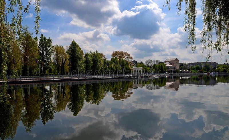 The island among the lake on which grow tall green trees against a blue sky with clouds