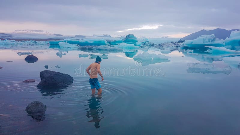 Island - ung man som får in i vattnet av glaciärlagun arkivbild Island - ung man som får in i vattnet av glaciärlagun arkivbild