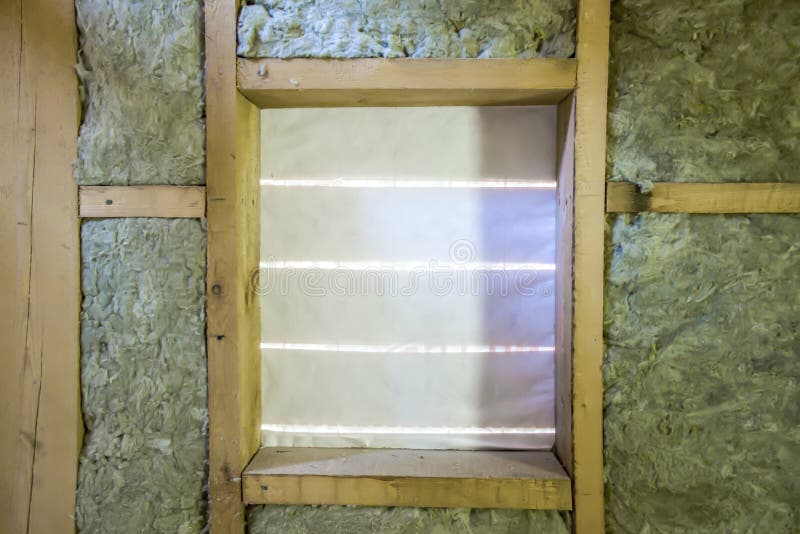 Isolamento della soffitta con la barriera della vetroresina ed il materiale di isolamento freddi Finestra nella casa di legno del fotografia stock libera da diritti Isolamento della soffitta con la barriera della vetroresina ed il materiale di isolamento freddi Finestra nella casa di legno del fotografia stock libera da diritti