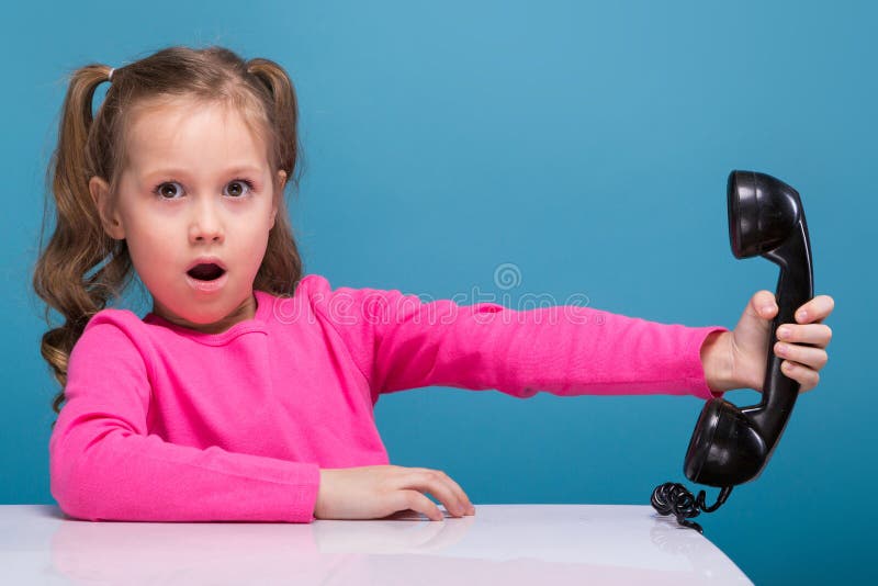 Attractive little cute girl in pink shirt with monkey and blue trousers hold empty poster and talks a phone