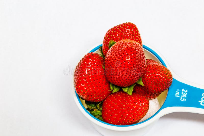 Isolated Close up, macrophotography, of Strawberries in a measuring cup on white background.