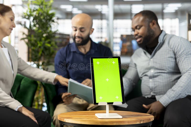 Isolated screen tablet next to workers looking over research documentation royalty free stock images