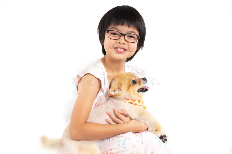 Isolerad asiatisk liten flicka f?r st?ende som rymmer den Pomeranian hunden med omsorg p? vit bakgrund E fotografering för bildbyråer Isolerad asiatisk liten flicka f?r st?ende som rymmer den Pomeranian hunden med omsorg p? vit bakgrund E fotografering för bildbyråer