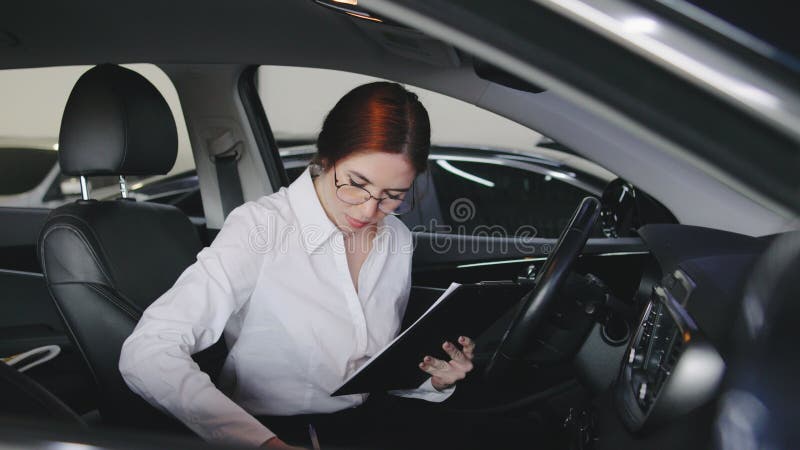 Ispezione di un'auto condotta da una donna all'interno di un veicolo in un impianto automobilistico durante le ore diurne stock footage