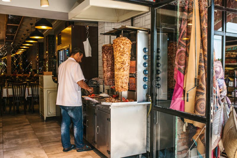 Istanbul Juni 15, 2017: den turkiska kocken är laga mat och skiva gyroskopdelar i restaurangen Skjutit i en studio royaltyfri bild Istanbul Juni 15, 2017: den turkiska kocken är laga mat och skiva gyroskopdelar i restaurangen Skjutit i en studio royaltyfri bild