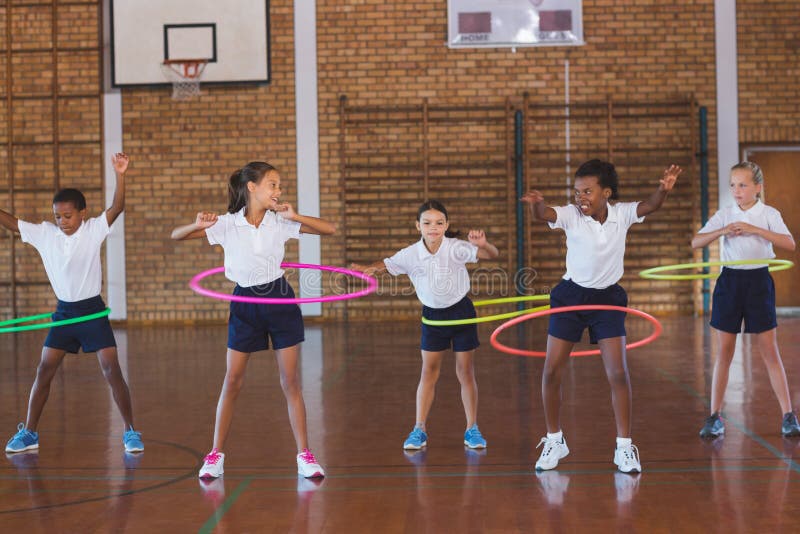 Istruisca i bambini che giocano con il hula-hoop dentro nel campo da pallacanestro immagine stock libera da diritti Istruisca i bambini che giocano con il hula-hoop dentro nel campo da pallacanestro immagine stock libera da diritti