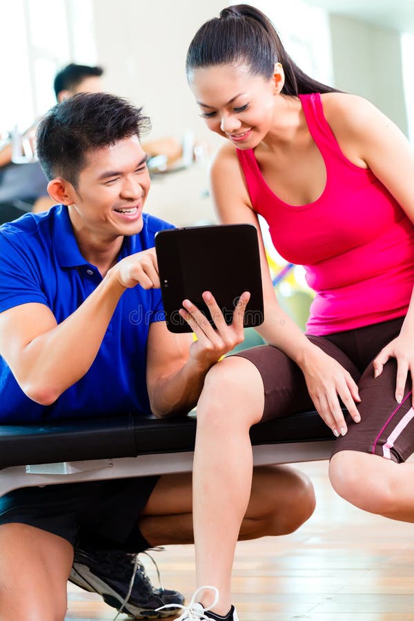Istruttore personale asiatico con la donna nella palestra di forma fisica immagine stock Istruttore personale asiatico con la donna nella palestra di forma fisica immagine stock