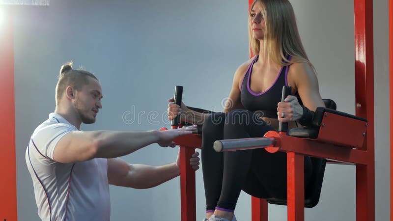 Istruttore personale che corregge il suo cliente durante l'esercizio nella palestra immagini stock libere da diritti Istruttore personale che corregge il suo cliente durante l'esercizio nella palestra immagini stock libere da diritti
