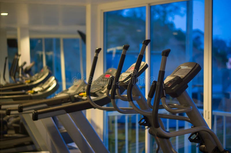 Istruttori trasversali ellittici in una palestra di forma fisica alla sera fotografie stock Istruttori trasversali ellittici in una palestra di forma fisica alla sera fotografie stock