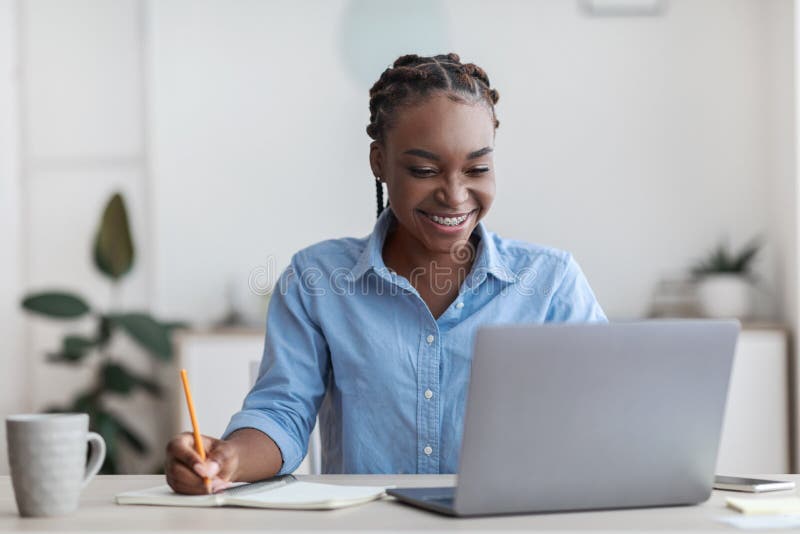 Istruzione online. Giovane studentessa nera usando il portatile a casa che prende atto fotografie stock libere da diritti