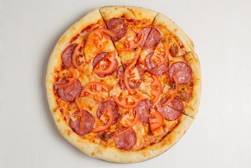 Italiaanse pizza met salamiworst, tomaat en kaas op een witte houten tafel
