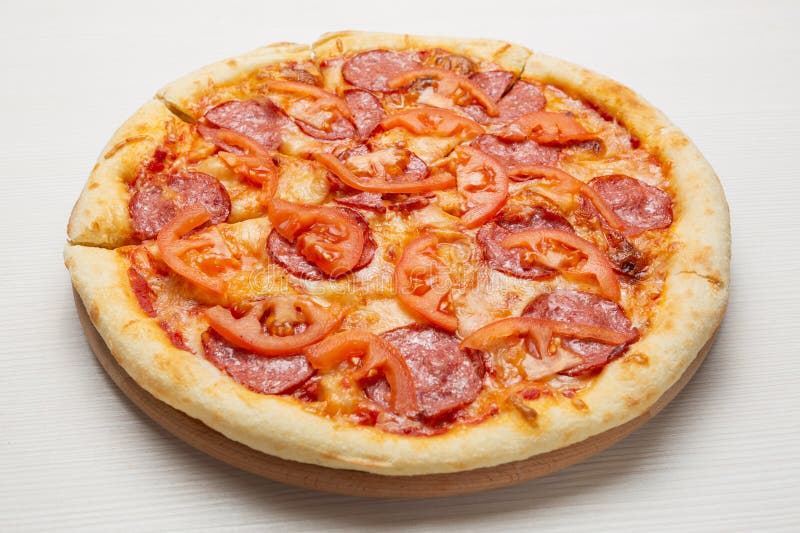 Italiaanse pizza met salamiworst, tomaten en kaas op een witte houten tafel