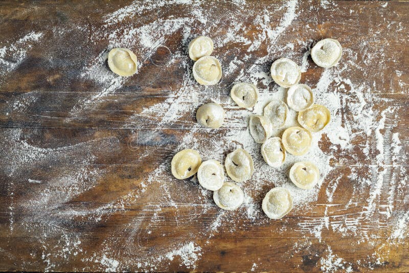 Raw homemade delicious traditional italian ravioli, dumplings with meat on dark wooden old surface, top view, copy space. Raw homemade delicious traditional italian ravioli, dumplings with meat on dark wooden old surface, top view, copy space