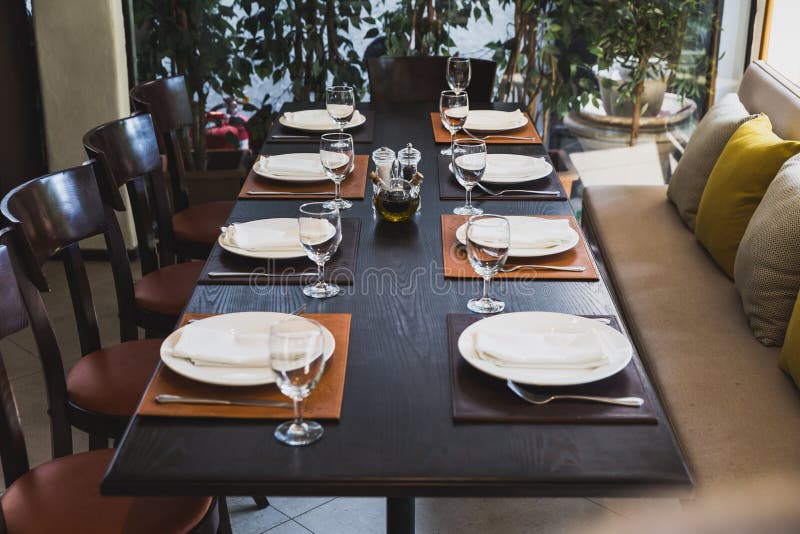 Italian dinner table for eight with cutleries, plates, glasses, napkins and naperies on the table stock photography Italian dinner table for eight with cutleries, plates, glasses, napkins and naperies on the table stock photography