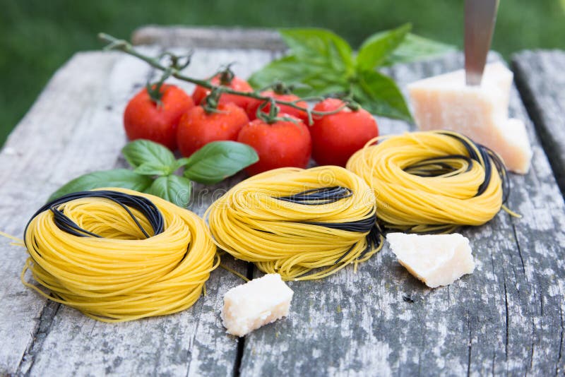 Italian food background with tomatoes, basil, spaghetti, parmesan, olive oil. Ingredients on old wooden table. stock image Italian food background with tomatoes, basil, spaghetti, parmesan, olive oil. Ingredients on old wooden table. stock image