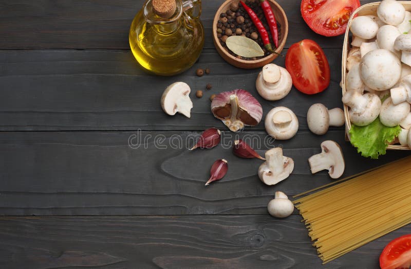 Italian food background, with tomatoes, parsley, spaghetti, mushrooms, oil, lemon, peppercorns on dark wooden table. Top view stock image Italian food background, with tomatoes, parsley, spaghetti, mushrooms, oil, lemon, peppercorns on dark wooden table. Top view stock image