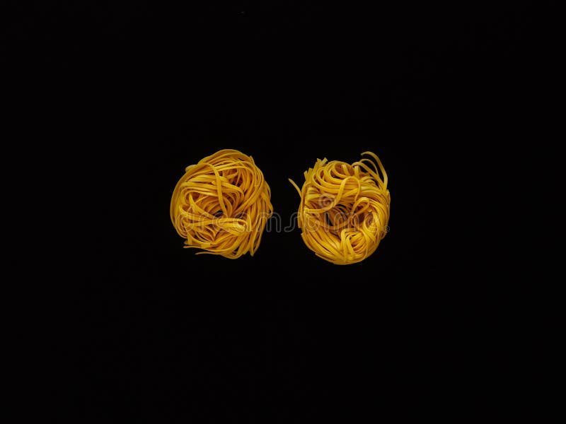 Italian noodle pasta uncooked over black background in studio from top view