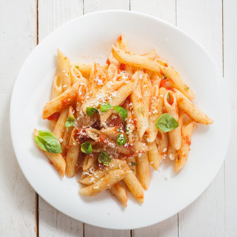 Italiano O tagliatelle speziato pomodoro salsa, fresco basilico un grattugiato parmigiano formaggio visualizzato da vicino più alto sul bianco piatto la piazza cittadina formato.