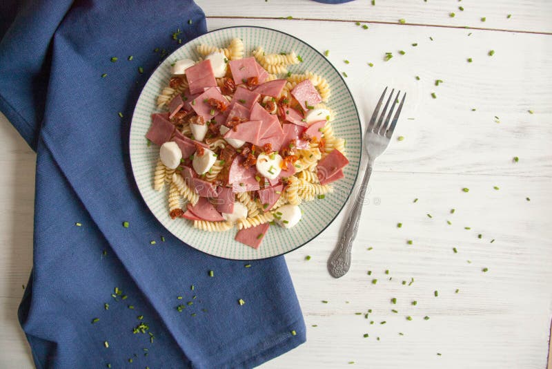 Italian salad with pasta, ham, mozzarella cheese and dried tomatoes