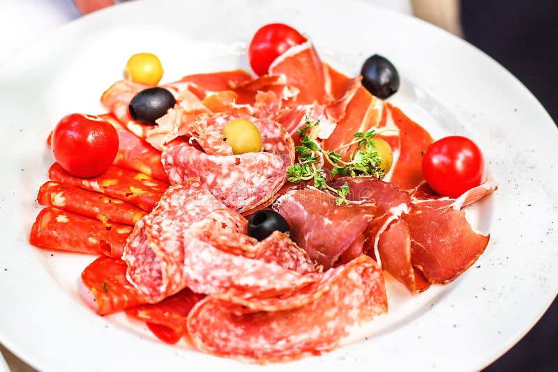 Italian salumi meat platter - prosciutto ham, salami olive and cherry tomato.