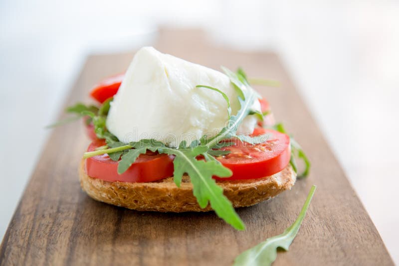 Italian style toast with light bread, arugula, tomato and mozzarella cheese