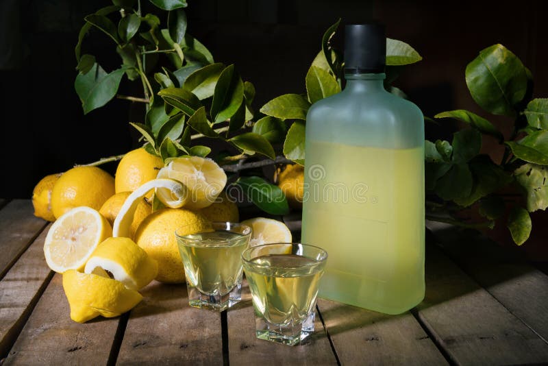 Italian typical digestive limoncello with fresh lemons on a old wooden background, low key royalty free stock photos Italian typical digestive limoncello with fresh lemons on a old wooden background, low key royalty free stock photos