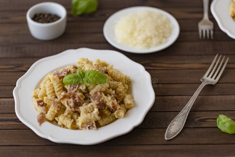 Italiano hecho en casa del carbonara de las pastas con el tocino, huevos, queso parmesano en la placa blanca en un fondo oscuro imágenes de archivo libres de regalías Italiano hecho en casa del carbonara de las pastas con el tocino, huevos, queso parmesano en la placa blanca en un fondo oscuro imágenes de archivo libres de regalías