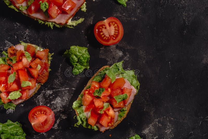 Italiano tradicional Bruschetta con los tomates, la salsa de la mozzarella, las hojas de la ensalada y el jam?n tajados en un fon fotografía de archivo libre de regalías Italiano tradicional Bruschetta con los tomates, la salsa de la mozzarella, las hojas de la ensalada y el jam?n tajados en un fon fotografía de archivo libre de regalías
