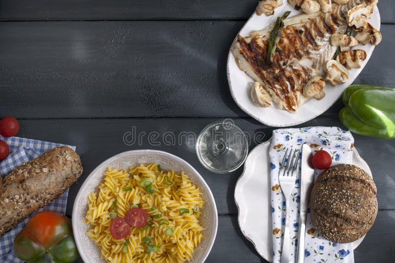 Italienische Teigwaren, gegrillter Fisch, frisches Brot auf einem schwarzen Hintergrund Köstliches italienisches Abendessen Kopie lizenzfreie stockfotos Italienische Teigwaren, gegrillter Fisch, frisches Brot auf einem schwarzen Hintergrund Köstliches italienisches Abendessen Kopie lizenzfreie stockfotos