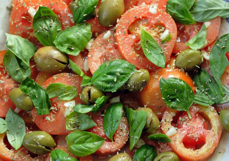 Typical salad of Southern Italy: tomatoes, basil torn manually, garlic, dry oregano, and pressed green olives. Typical salad of Southern Italy: tomatoes, basil torn manually, garlic, dry oregano, and pressed green olives