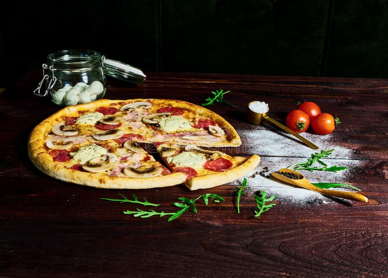 Italienischer Schnellimbiß Köstliche heiße Pizza geschnitten und auf hölzerner Servierplatte mit Bestandteilen, Abschluss herauf stockfoto Italienischer Schnellimbiß Köstliche heiße Pizza geschnitten und auf hölzerner Servierplatte mit Bestandteilen, Abschluss herauf stockfoto