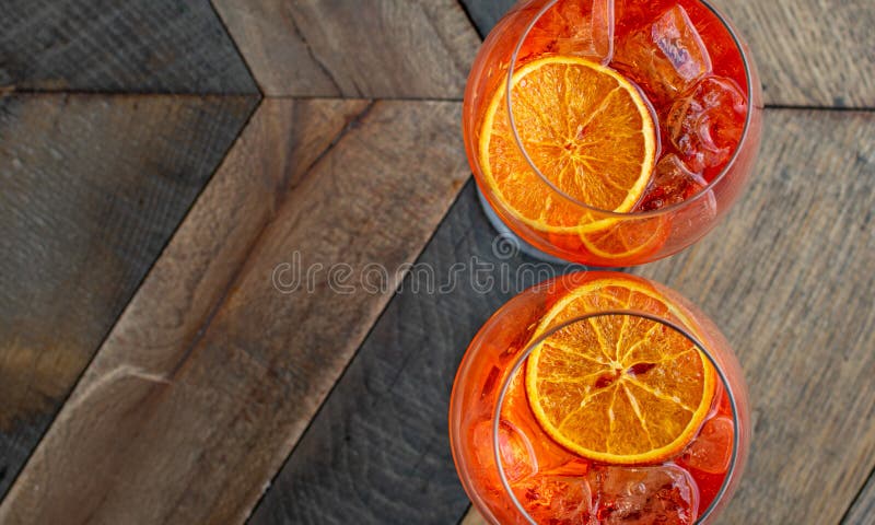 Florence, Tuscany / Italy. - May й4, 2018. Italian aperitif `aperol stpritz` with ice and a slice of orange in two large round glasses on a wooden table in a bar in Italy. Florence, Tuscany / Italy. - May й4, 2018. Italian aperitif `aperol stpritz` with ice and a slice of orange in two large round glasses on a wooden table in a bar in Italy